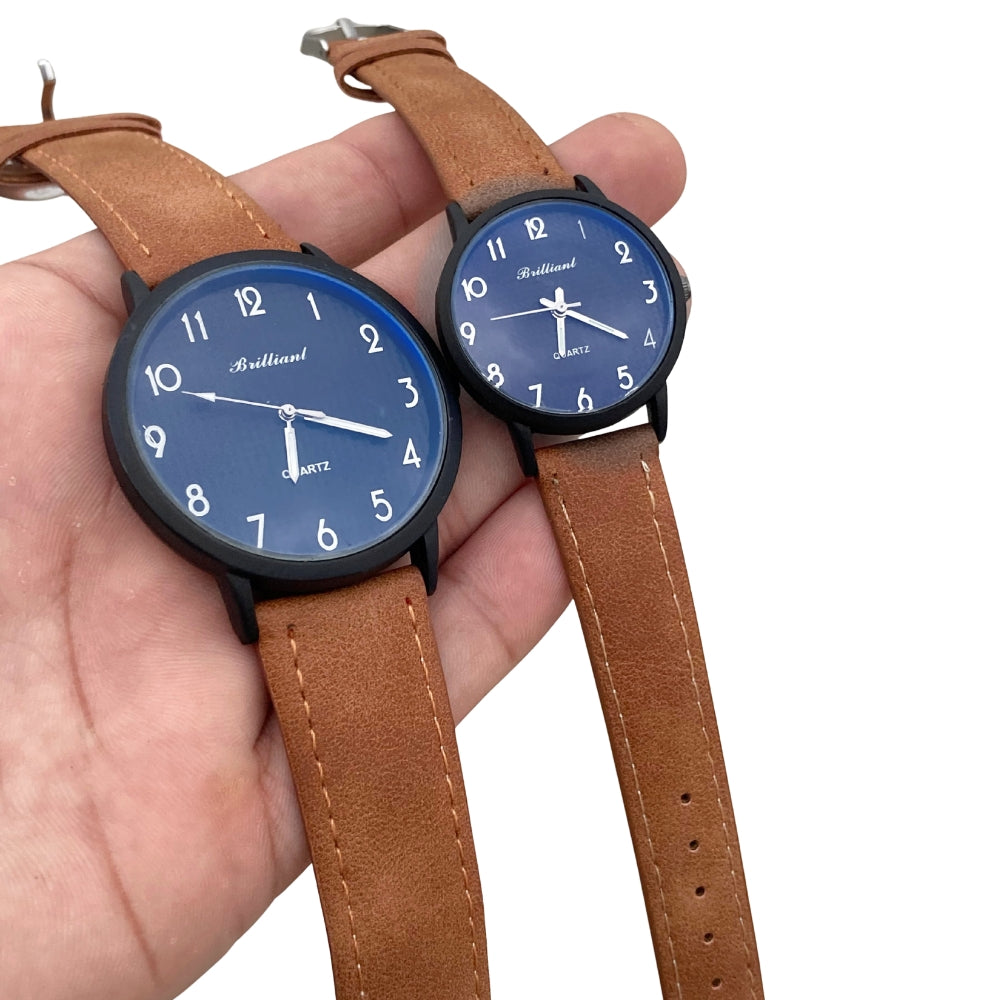 Two watches with blue faces and brown leather straps held in a hand against a white background.
