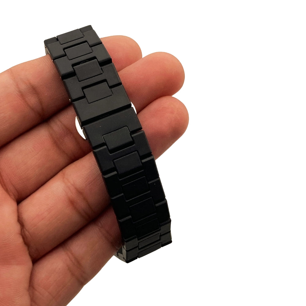 Black metal watch strap held in a hand against a white background