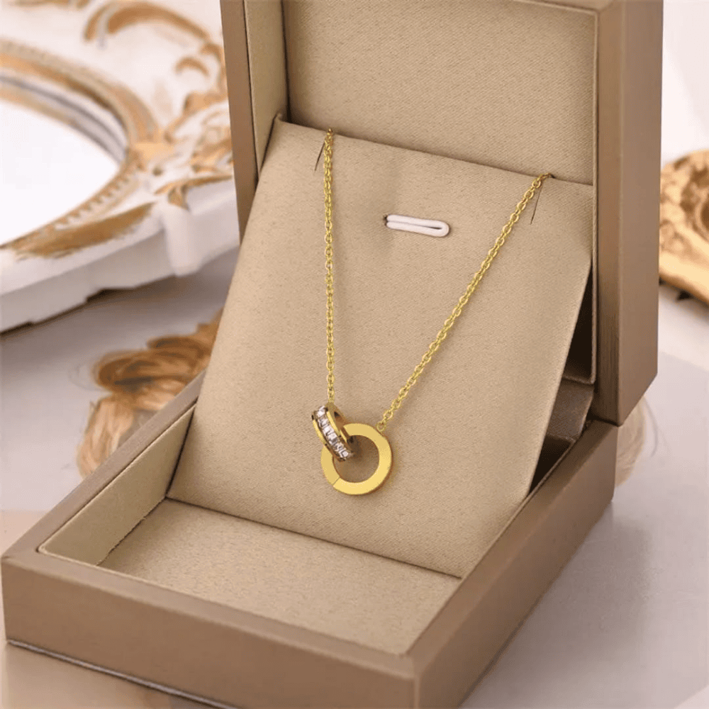 Side front view of gold plated branded locket set in its box