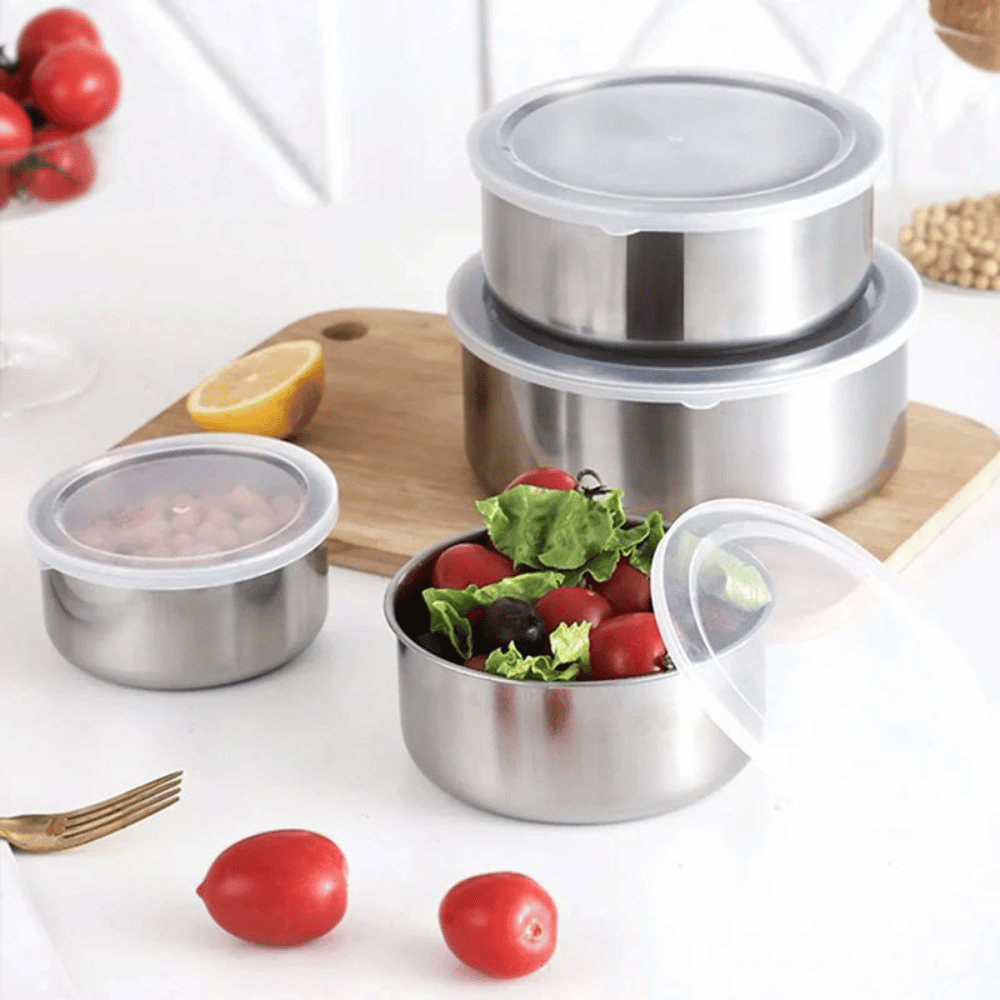 Set of stainless steel food containers with food on a white background