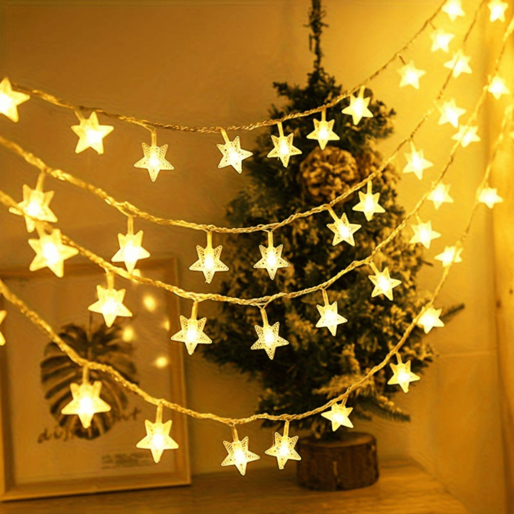 Star-shaped string lights hanging above a Christmas tree in a cozy room.