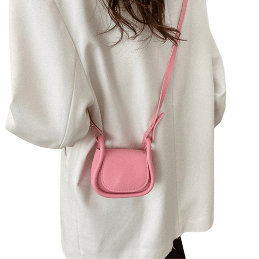 Pink crossbody bag worn by a person in a white coat on a white background