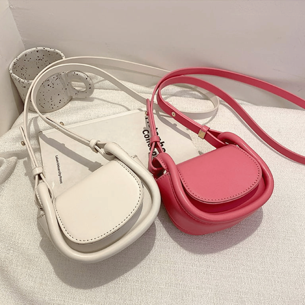Two small handbags, one beige and one pink, on a light surface.