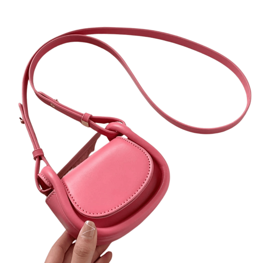 Pink crossbody bag held by a hand on a white background