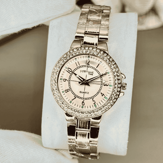 Silver wristwatch with decorative band on a white stand