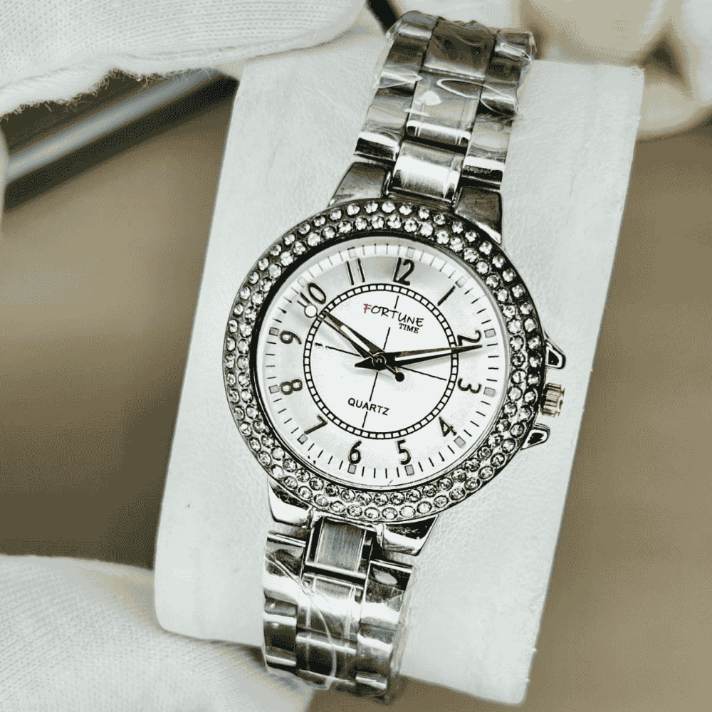 Silver wristwatch with gemstone accents on a white cushion