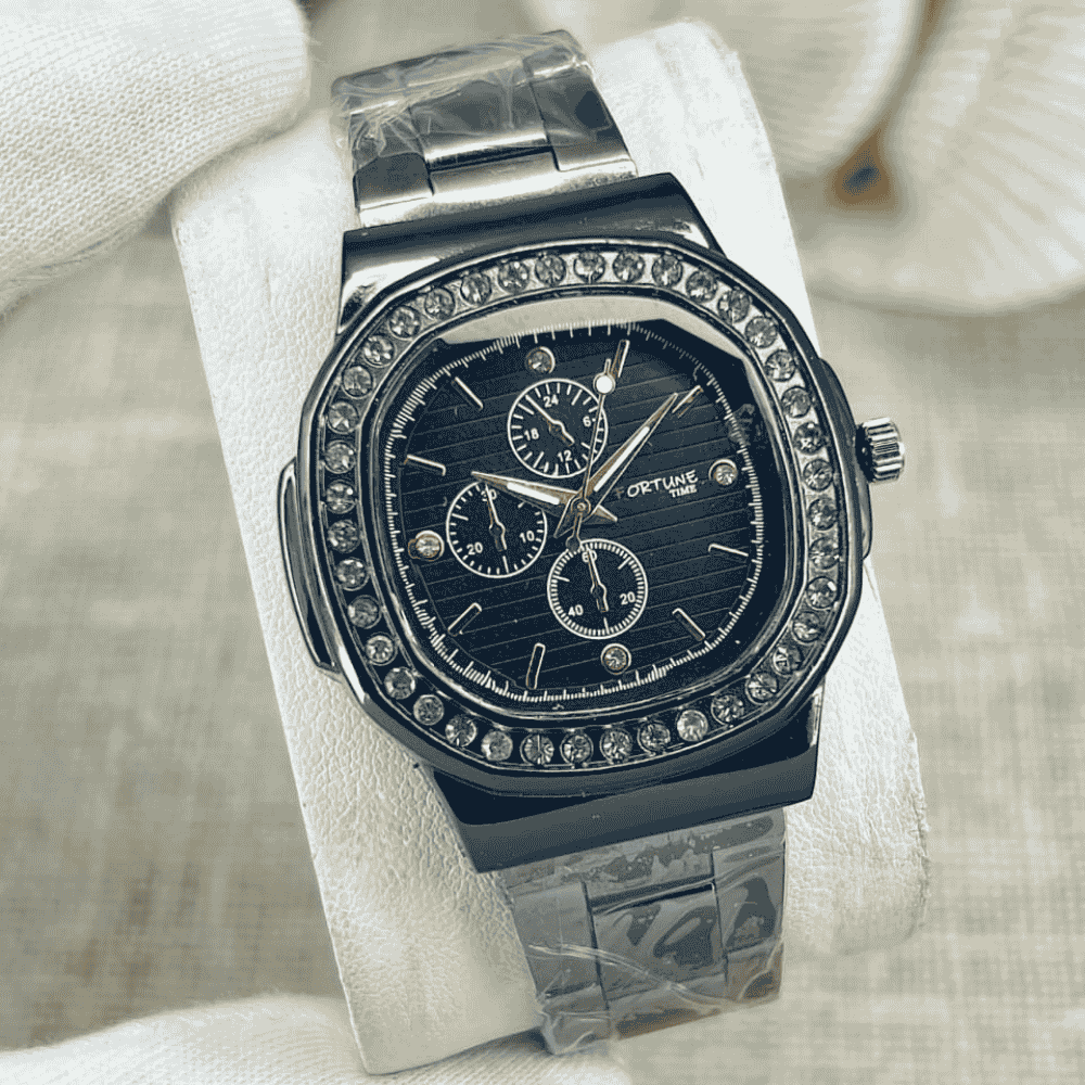 Luxury watch with a black face and silver band on a white cushion