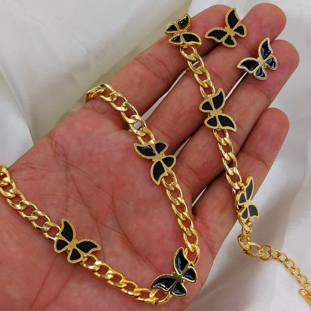 Gold chain with black butterfly pendants held in a hand against a white background