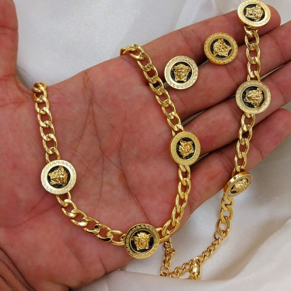 Gold chain necklace and earrings on a hand against a white background