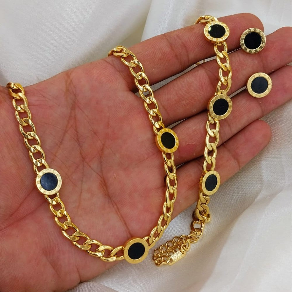 Gold chain with black circular accents held in a hand against a white background