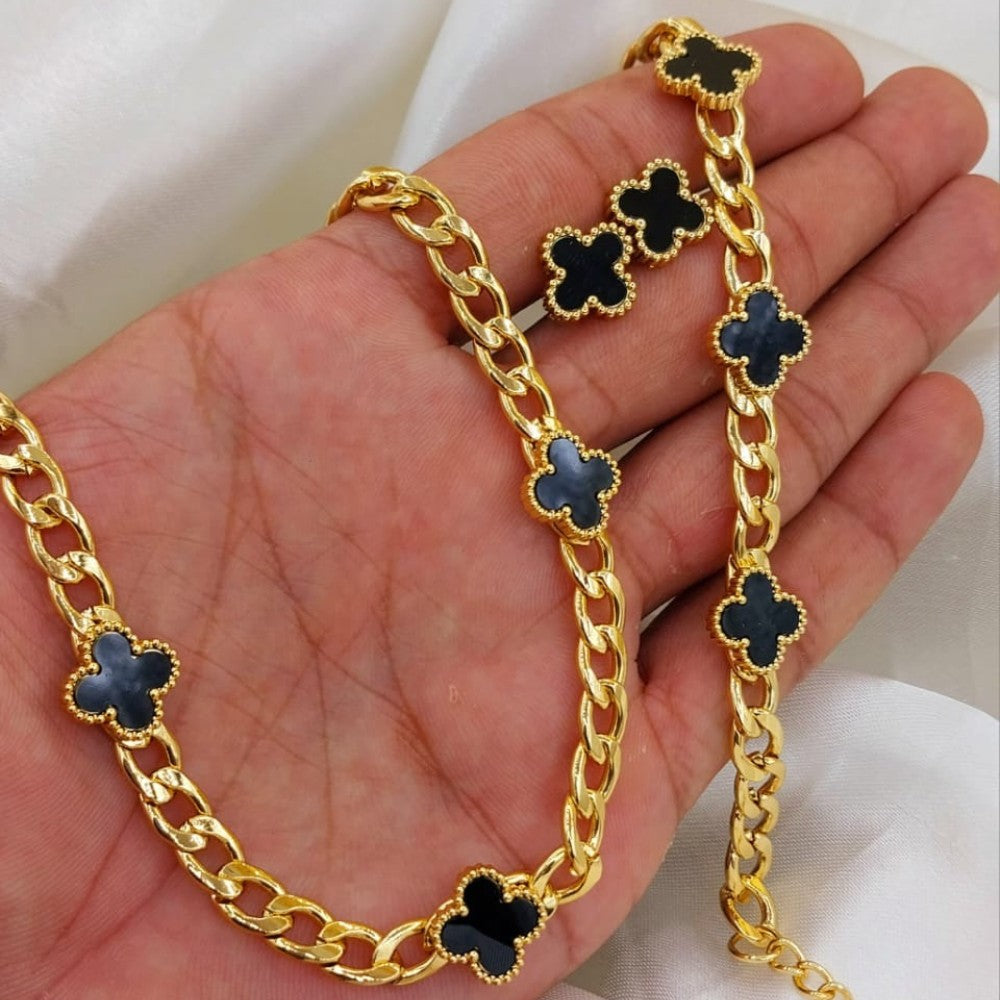 Gold chain necklace with black clover-shaped pendants held in a hand.