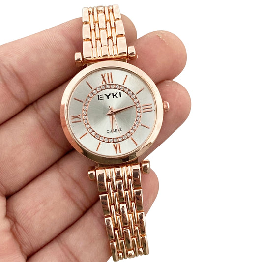Rose gold watch with 'EYKI' branding held in a hand against a white background
