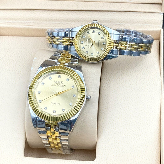 Two watches, one gold and one silver, on a beige cushioned surface.