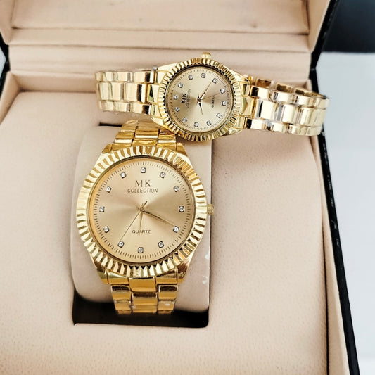 Gold wristwatch with MK Collection branding on a beige cushioned surface
