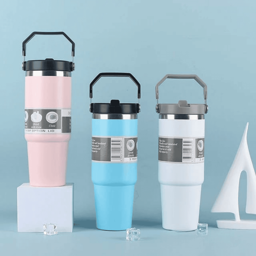 Three insulated travel mugs in pink, blue, and white with black lids on a light blue background.