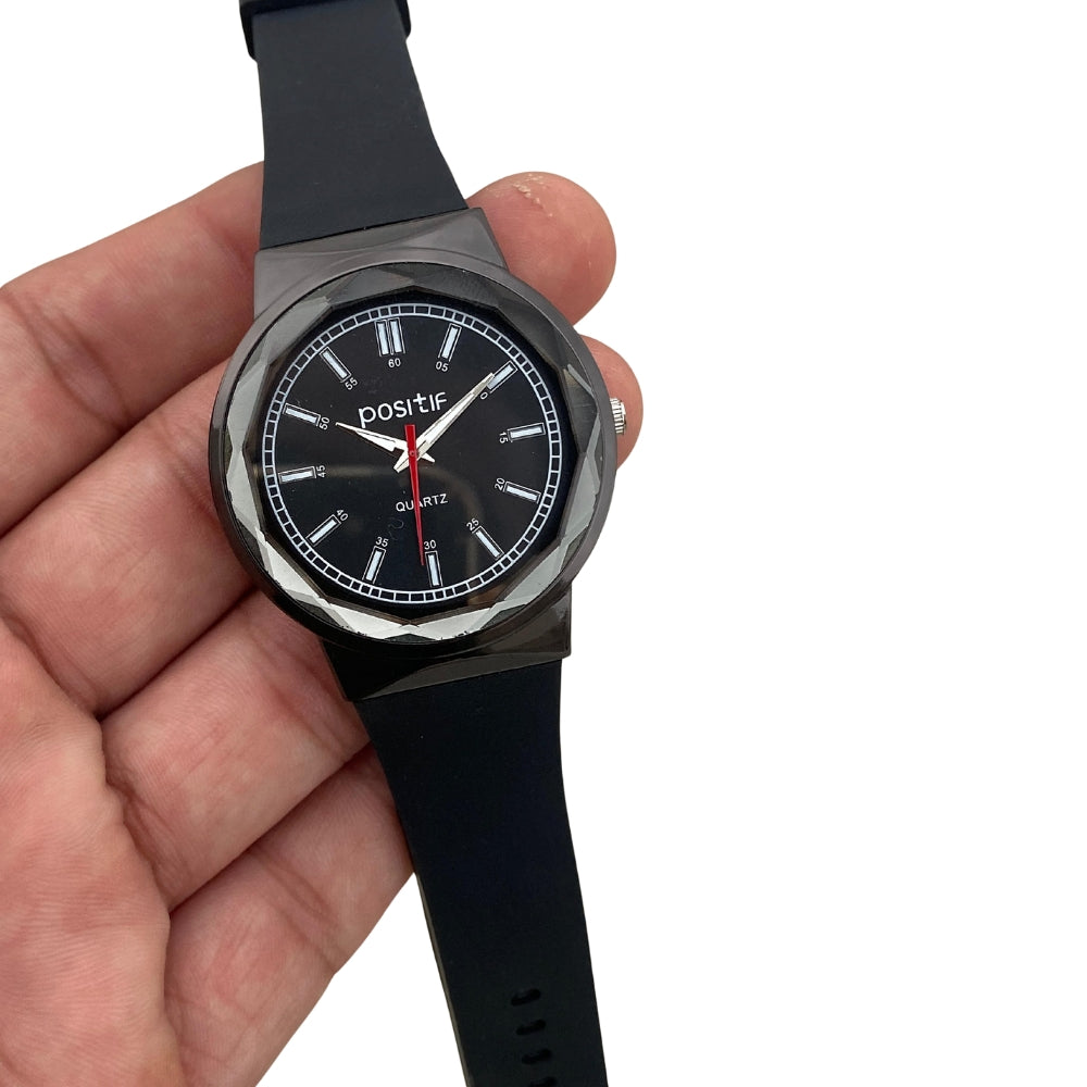 Black wristwatch held in a hand with a white background