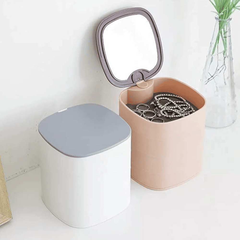 Jewelry organizer with a mirror on top, containing necklaces, on a white surface.