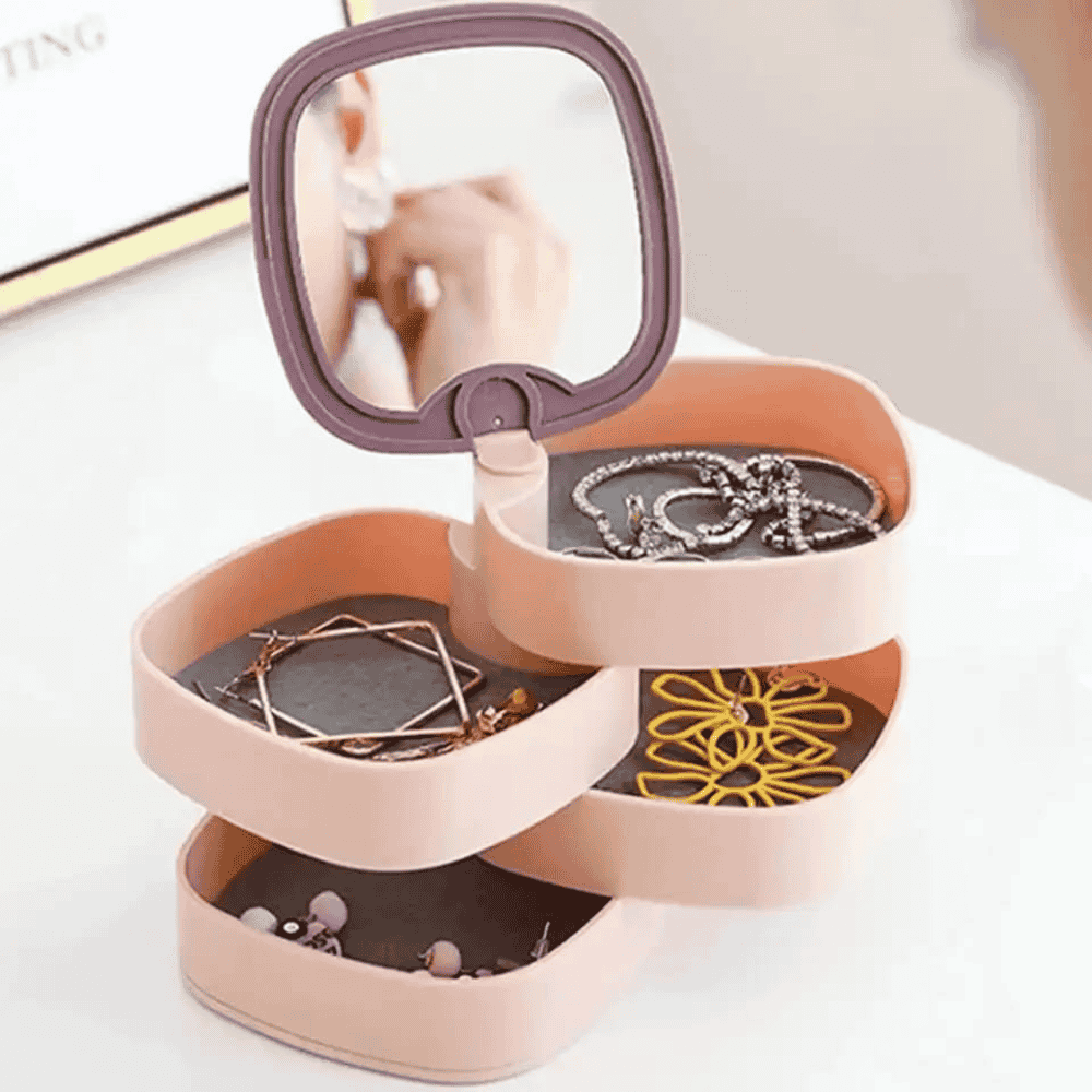 Pink jewelry organizer with mirror lid containing necklaces and earrings on a white background