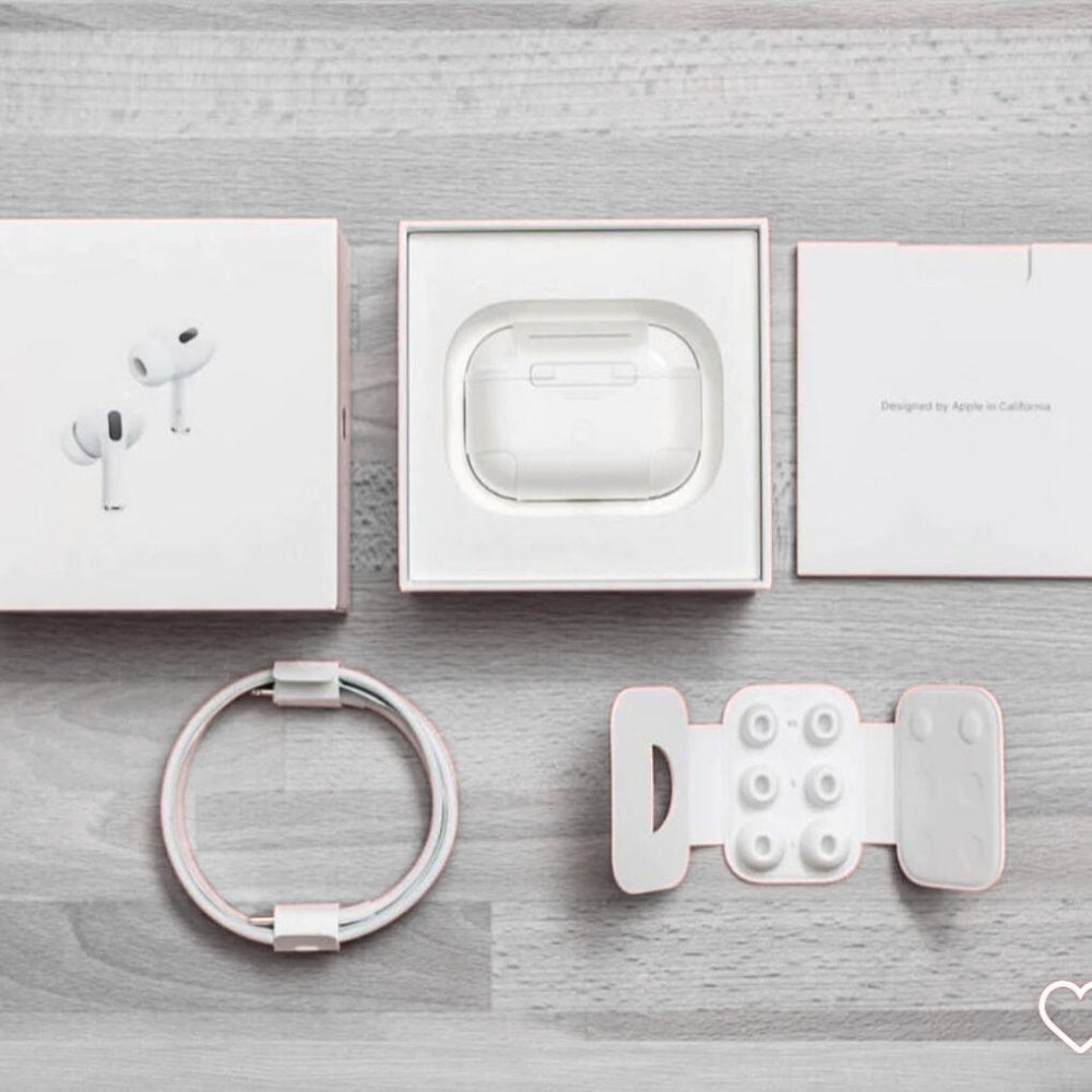 White electronic accessories including earbuds, charging case, ring, and phone stand on a gray wooden surface.