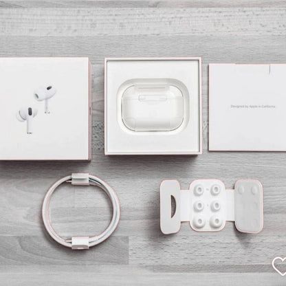 White electronic accessories including earbuds, charging case, ring, and phone stand on a gray wooden surface.