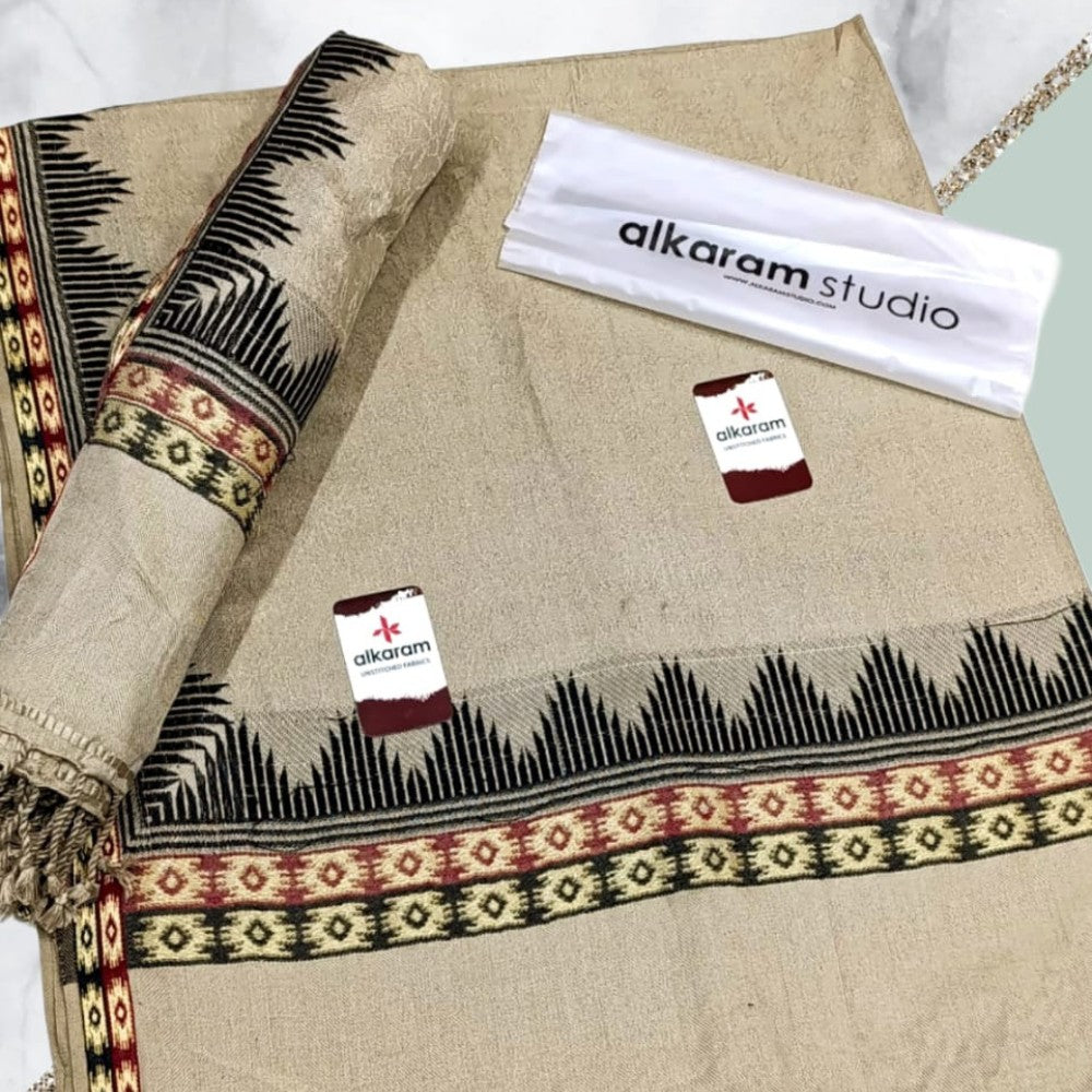 Textile with black and red patterns on a beige background, featuring 'alkaram studio' branding.