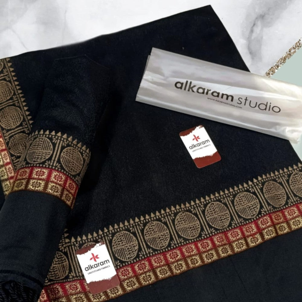 Black fabric with intricate patterns and 'alkaram studio' branding.