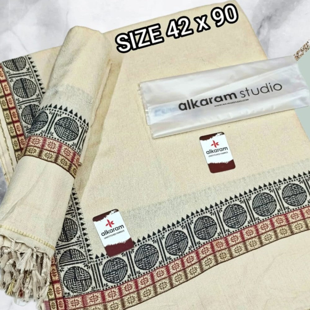 Beige towel with decorative patterns and 'alkaram studio' branding, size 42 x 90.