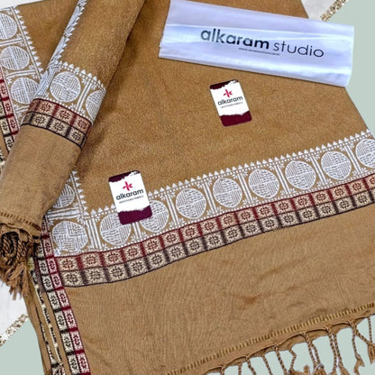 Brown fabric with intricate patterns and 'alkaram studio' branding.