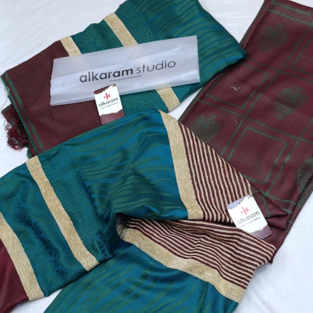 Two patterned scarves with 'alkaram studio' branding on a white background
