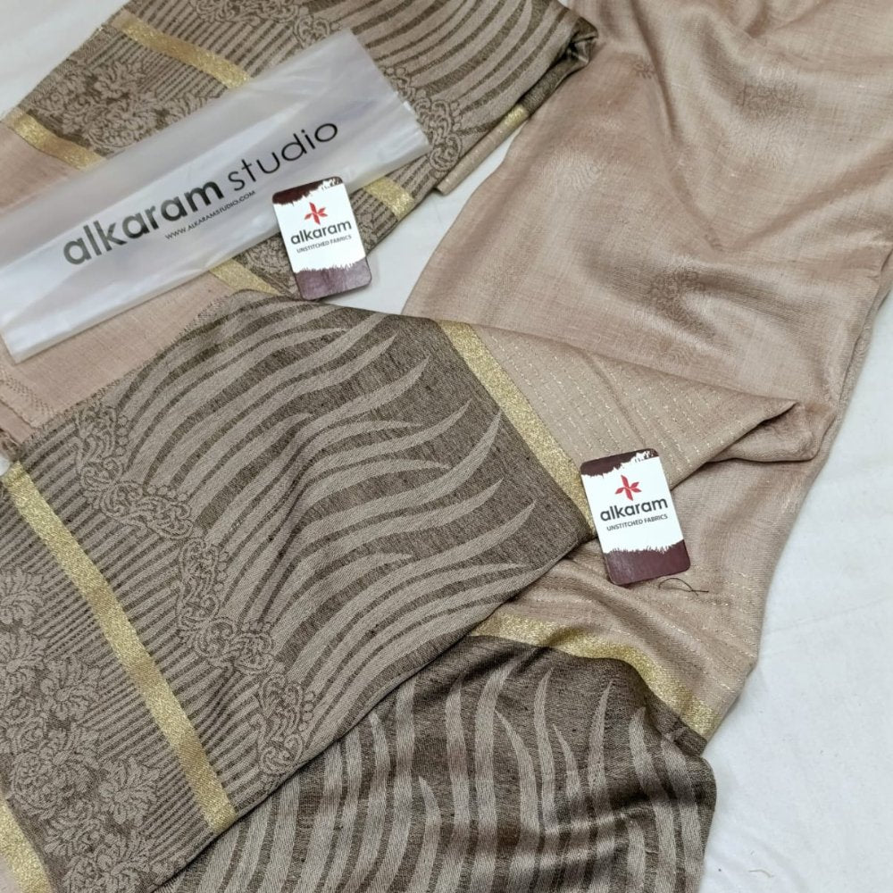 Brown fabric with gold accents and 'alkaram studio' branding on a white background