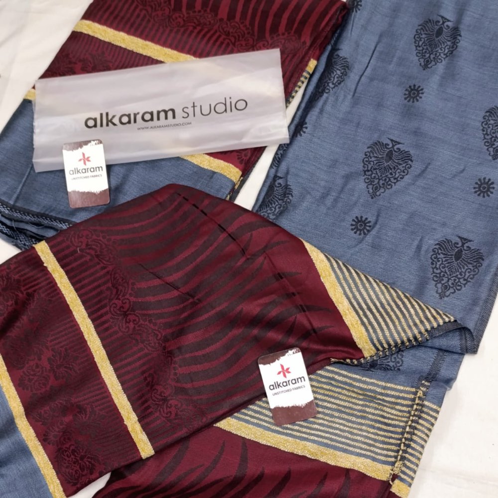 Two patterned fabrics with 'alkaram studio' branding on a white background