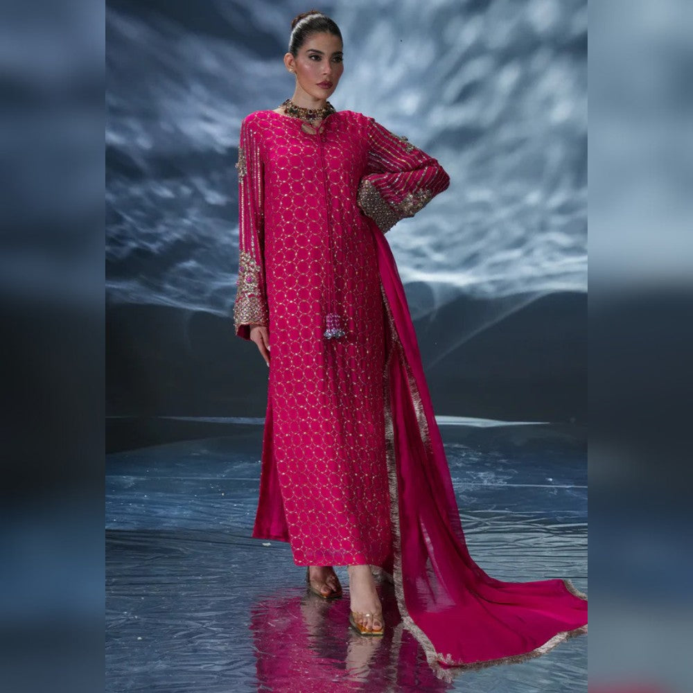 Woman wearing a pink traditional outfit with intricate patterns on a reflective surface.