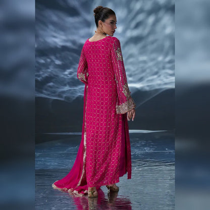 Woman in a pink traditional outfit with gold embroidery on a reflective surface.