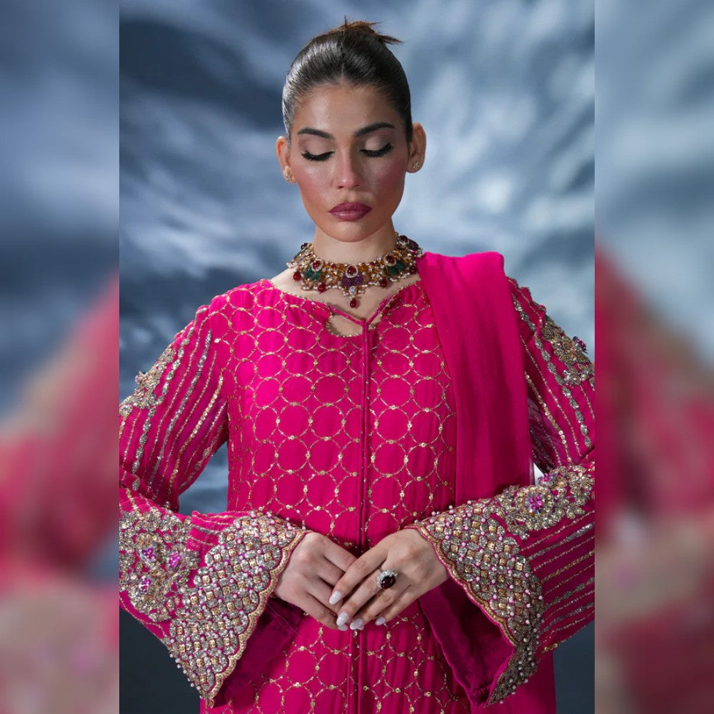 Woman wearing a pink traditional outfit with intricate designs and jewelry against a blurred background