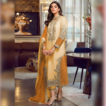 Woman in a yellow and orange embroidered traditional outfit in a stylish room.