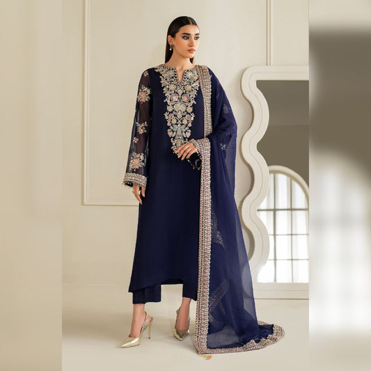 Woman wearing a navy blue embroidered outfit with a long dupatta in a neutral setting