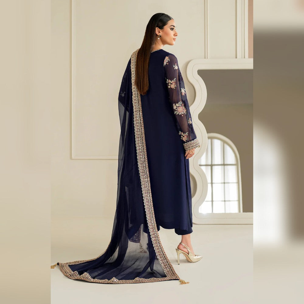 Woman in a navy blue traditional outfit with a long, embroidered scarf in a well-lit room.