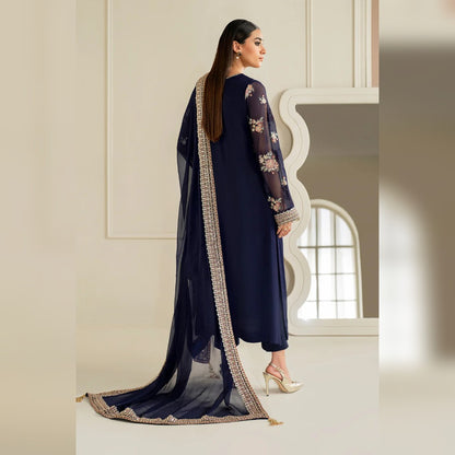 Woman in a navy blue traditional outfit with a long, embroidered scarf in a well-lit room.