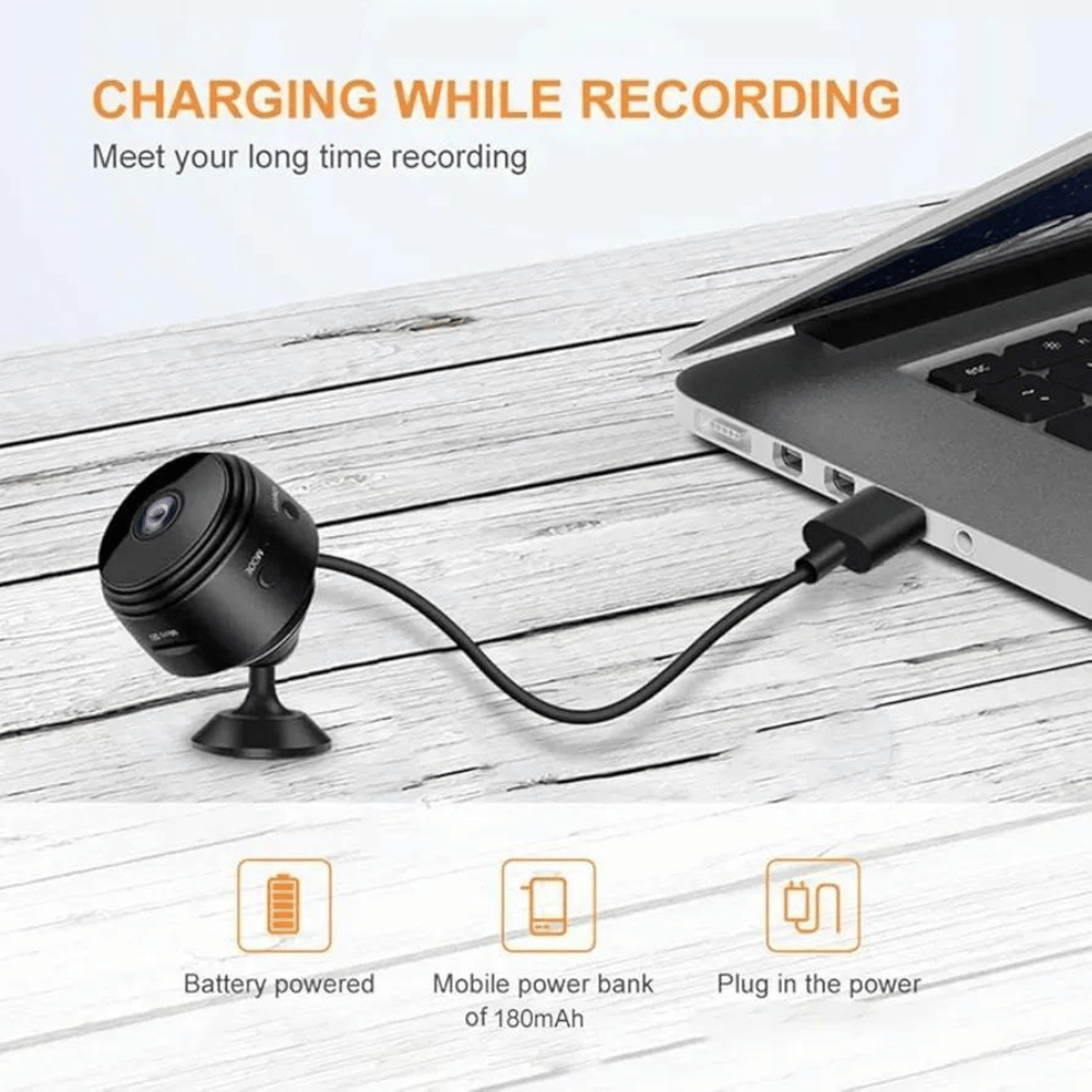 Small camera with power cable connected to a laptop on a wooden surface, with text about charging and recording.