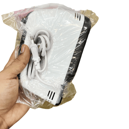 White electronic device with black accents and a cable, held in a clear plastic bag by a hand.