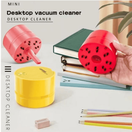 Mini desktop vacuum cleaner with colorful design on a desk with books and stationery items.