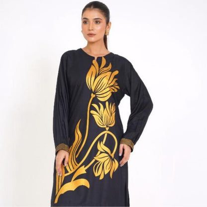 Woman wearing a black dress with gold floral patterns on a white background