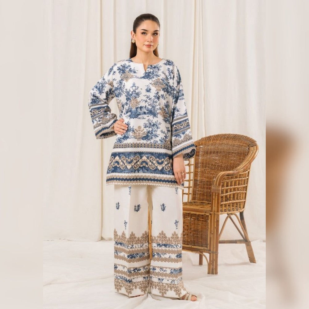 Woman wearing a blue and white patterned outfit standing in front of a white curtain with a wicker chair.