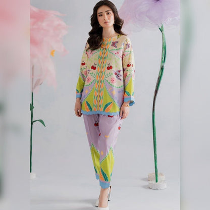 Woman wearing a colorful outfit with floral patterns in front of large flowers.