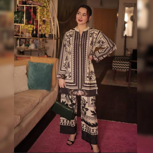 Woman in a patterned outfit standing in a room with a couch and decorative items.