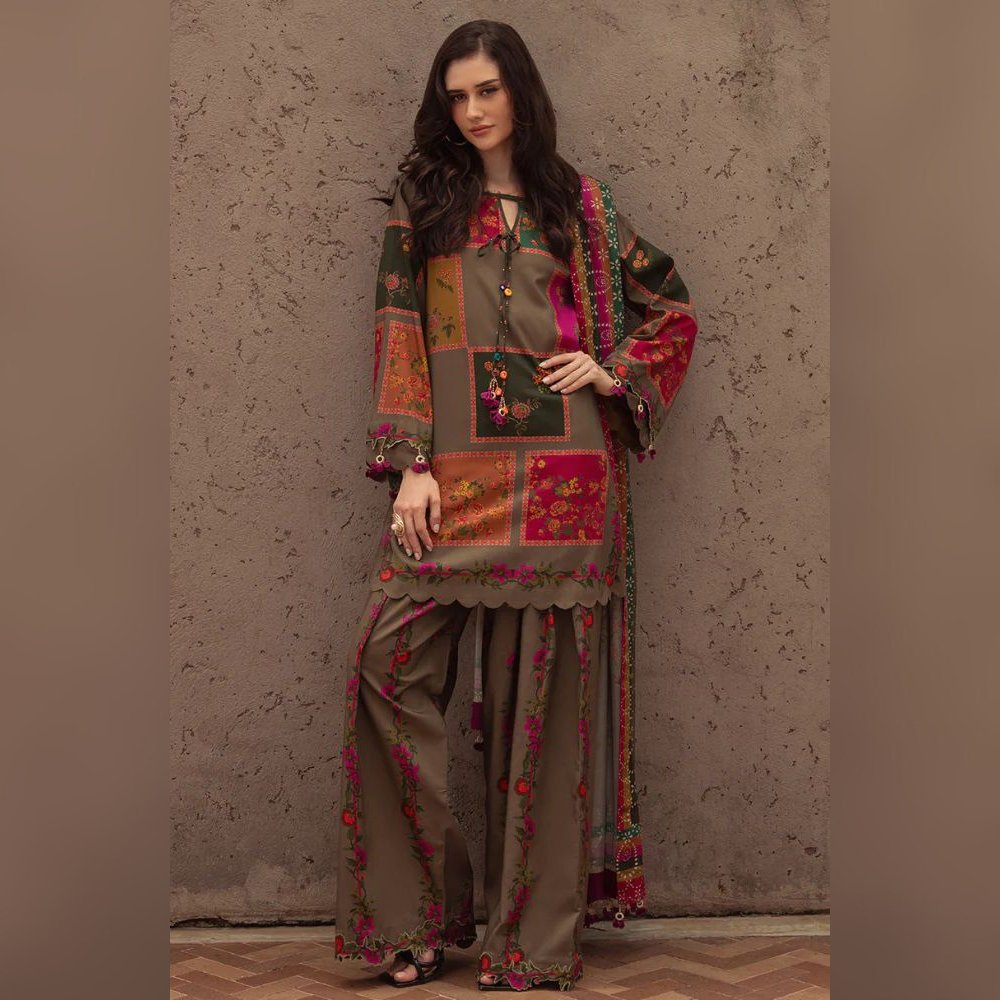 Woman wearing a traditional embroidered outfit against a textured wall.