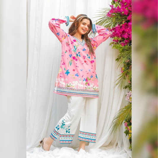 Woman wearing a pink floral dress with white pants in a decorated indoor setting.