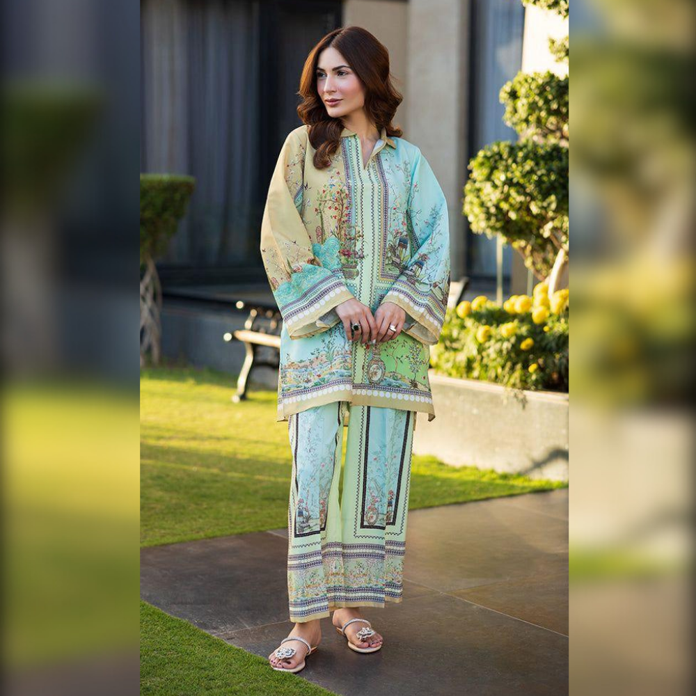 Woman in a light blue and green embroidered outfit standing outdoors.