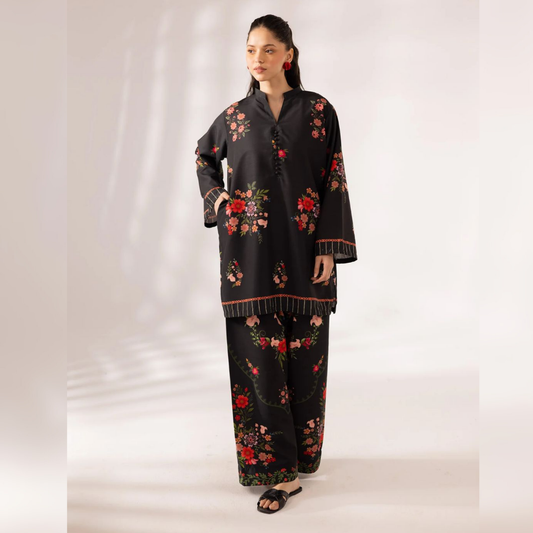 Woman wearing a black outfit with floral embroidery on a white background