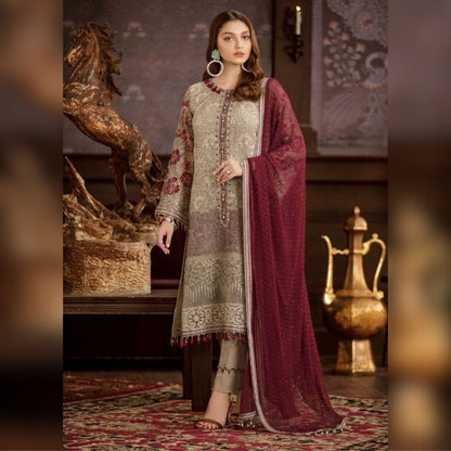 Woman in traditional embroidered outfit with a maroon dupatta in an ornate room.